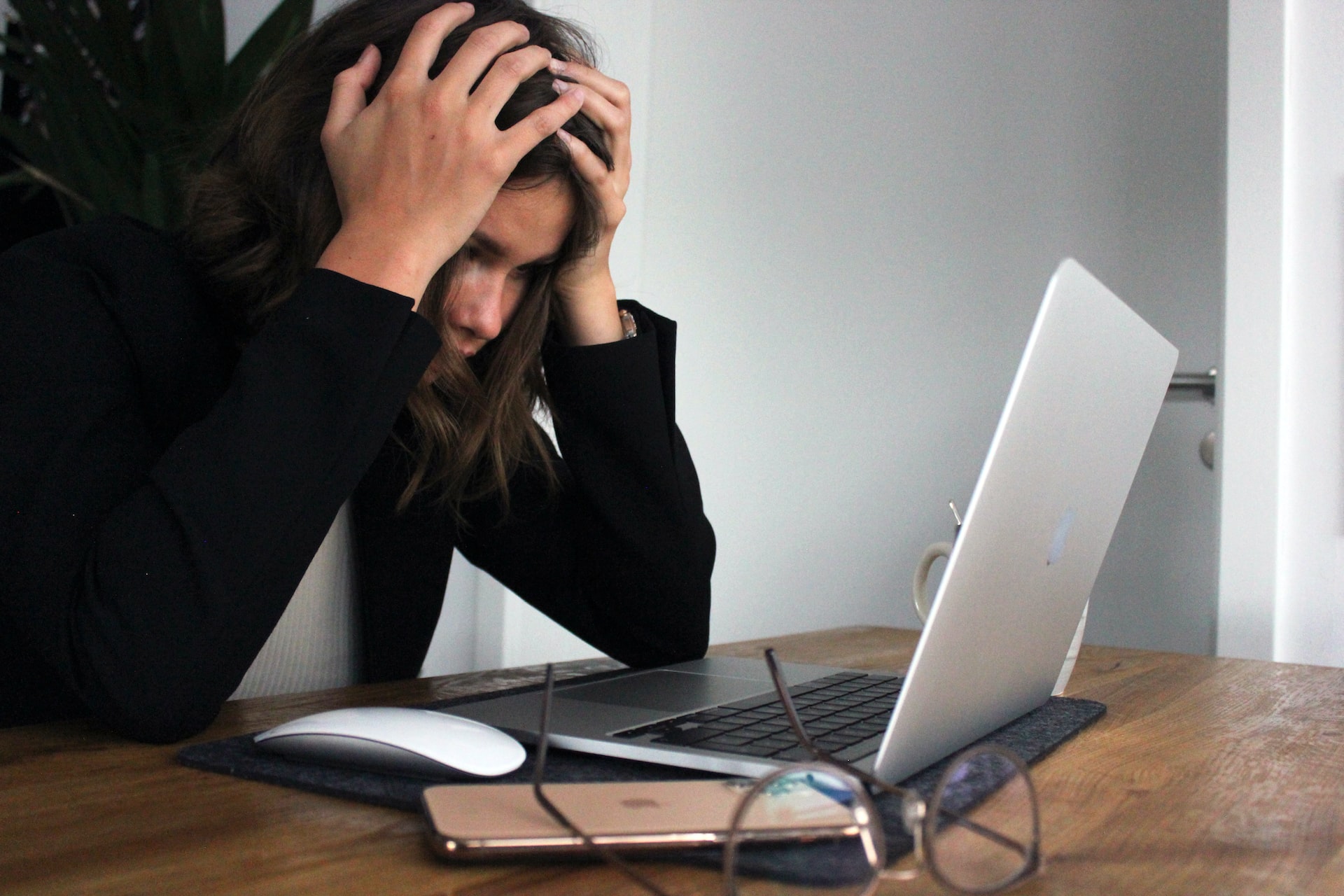A woman looking stressed and frustrated at a laptop
